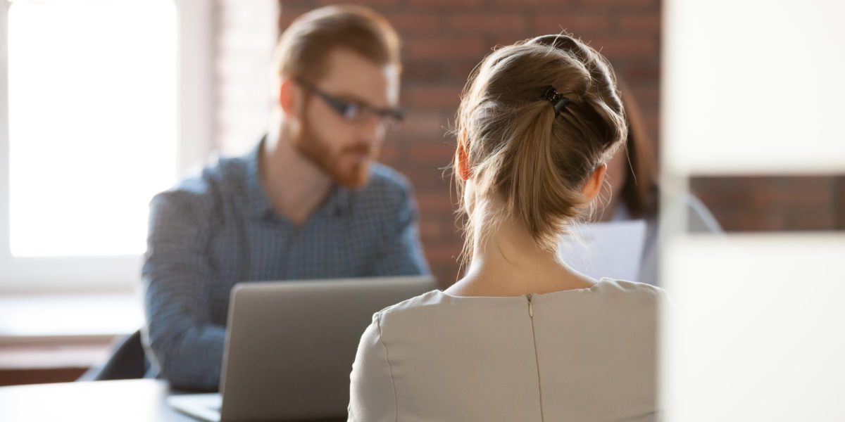 Rear view at young woman applicant seeker at job interview